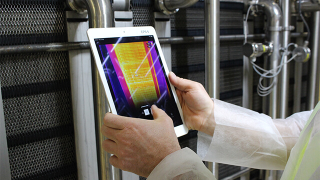 man holding ipad next to heat exchanger