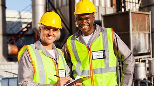 Two smiling engineers outside chemical plant