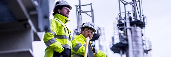 Two oil refinery workers discussing outside